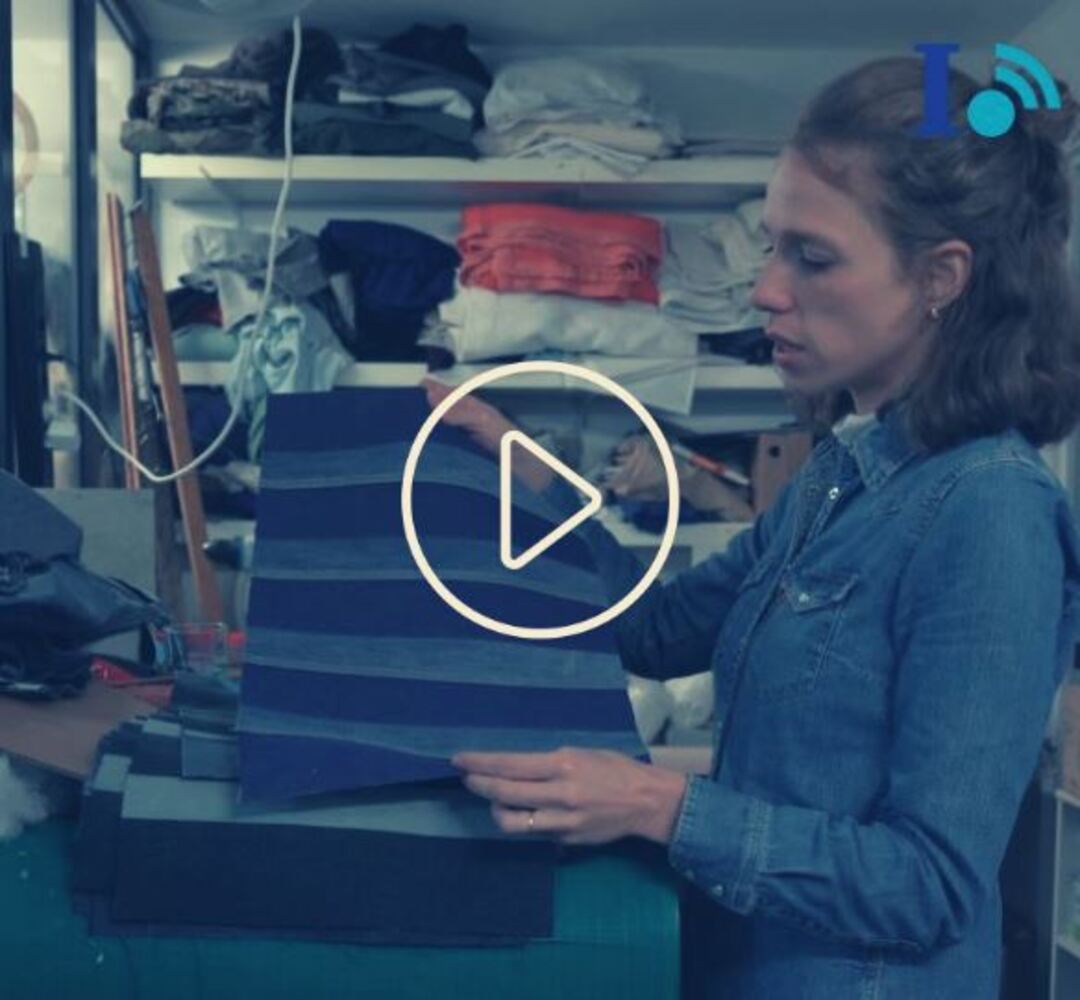 Une femme montre son travail de création d'un coussin avec des jeans issus de récupération.